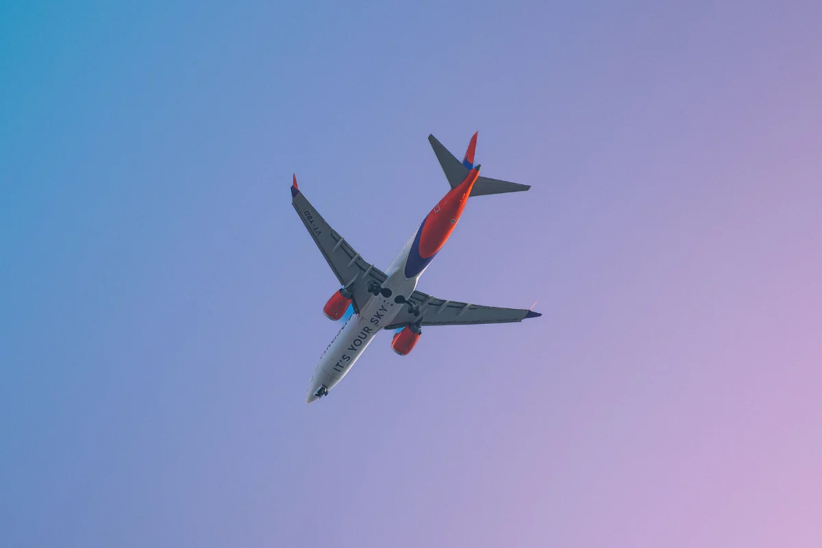 Commercial airplane flies overhead against a blue and purple-tinted sky.