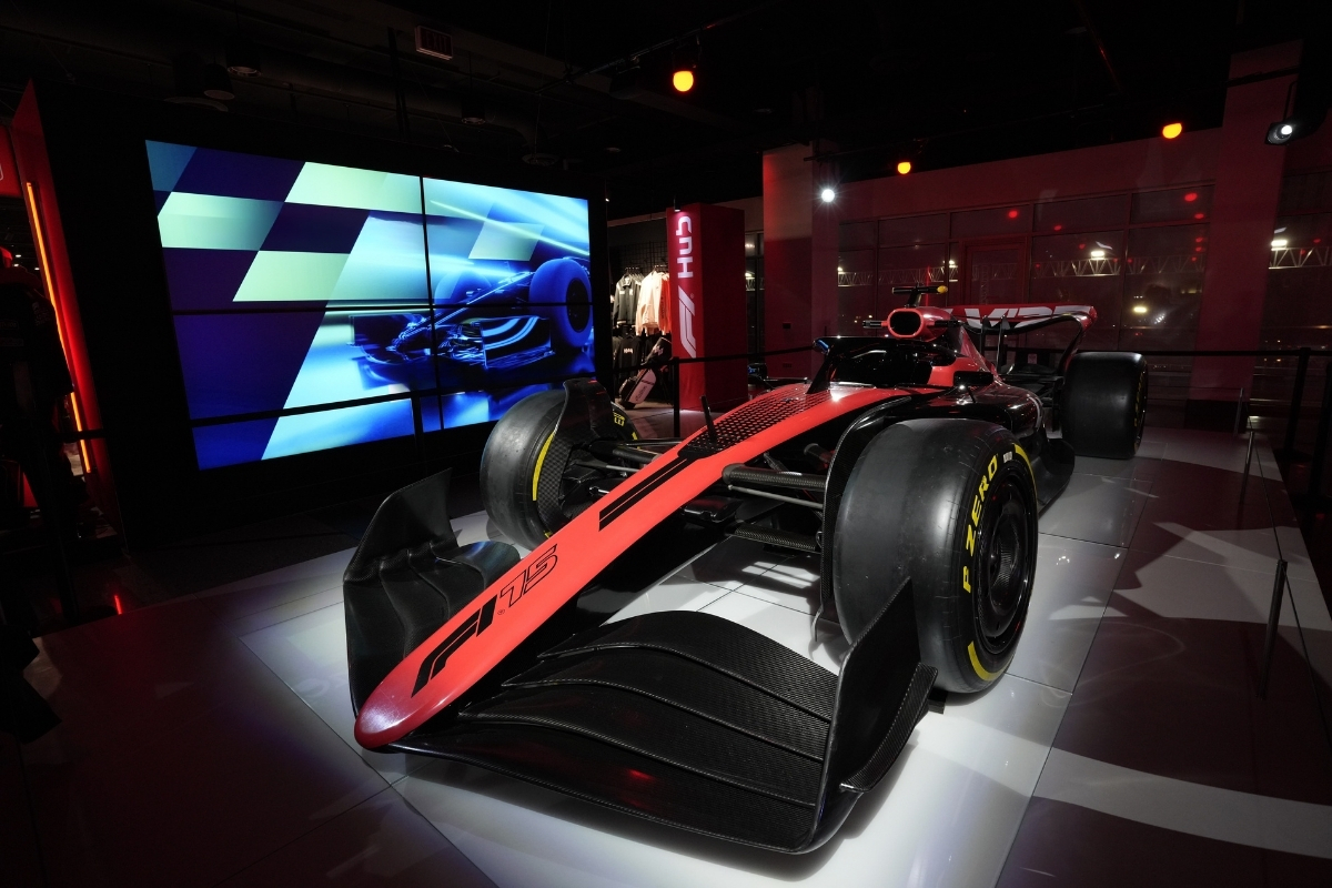 Panelists speak on a brightly lit stage surrounded by immersive racing-themed graphics and set design.