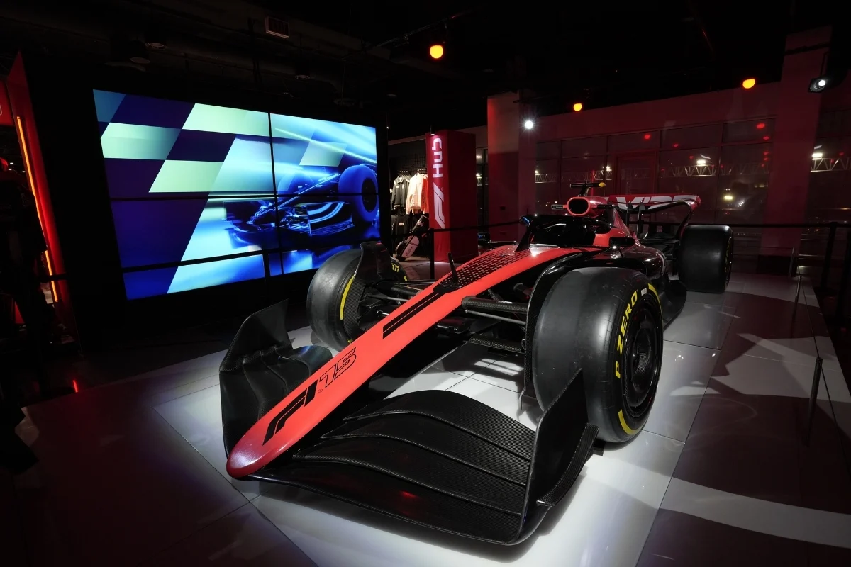 Panelists speak on a brightly lit stage surrounded by immersive racing-themed graphics and set design.