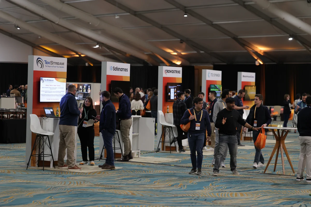 Attendees network and explore exhibitor booths in a spacious conference trade show hall.